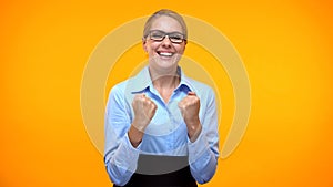 Excited business woman showing success gesture orange background, career goal
