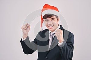 Excited businessman in black suit and santa hat isoalted on whit