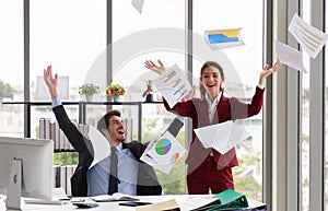 Excited businessman and businesswoman throwing papers in air