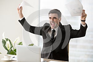 Excited businessman celebrating business success, holding papers