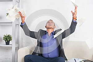 Excited businessman throwing papers at the office