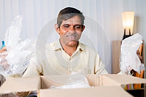 Excited businessman unboxing or opening cardboard box package or parcel - concept of goods bought from internt, happy