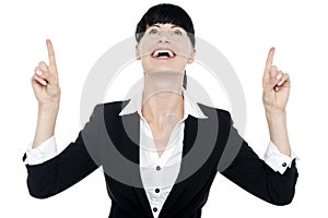 Excited businesswoman looking ad pointing upwards