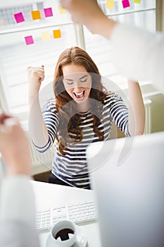 Excited businesswoman punching in air at creative office