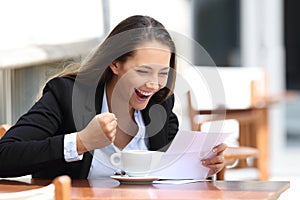 Excited businesswoman reading a letter outdoors