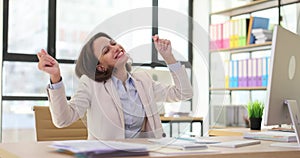 Excited businesswoman sitting at table and experiencing euphoria of winning online lottery