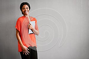 Excited businesswoman smiling at camera while holding a digital tablet