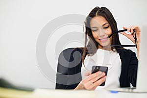 Excited businesswoman winning after achievement reading smart phone sitting in a desktop at office