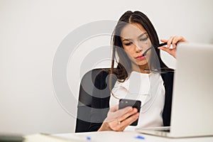 Excited businesswoman winning after achievement reading smart phone sitting in a desktop at office