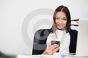 Excited businesswoman winning after achievement reading smart phone sitting in a desktop at office