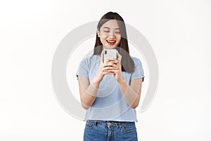 Excited carefree amused asian girl taking picture photographing girlfriend using smartphone camera hold phone look