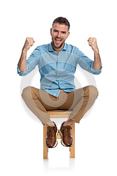 Excited casual guy with beard holding fists up and cheering