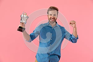 Excited casual guy holding trophy and celebrating victory
