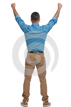 Excited casual man celebrating succes with his arms up