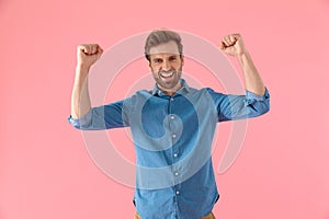 Excited casual man smiling and holding fists up celebrating