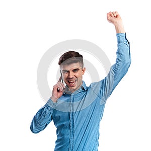 Excited casual man talking on the phone is celebrating success