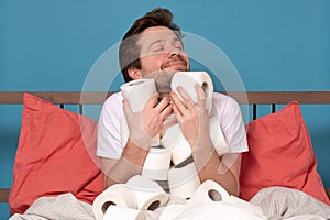 Excited caucasian man holding a pile of toilet paper isolated on blue background