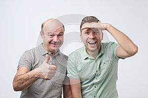 Excited caucasian men father and son are surprised showing thumb up
