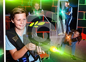 Excited boy aiming laser gun at other players during laser tag g