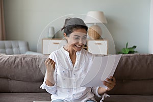 Excited cheerful young Indian woman getting good news letter