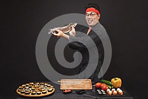 Excited chef with fish isolated black background