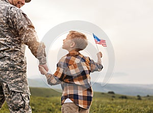 Excited child with american flag holding his father& x27;s hand reunited with family