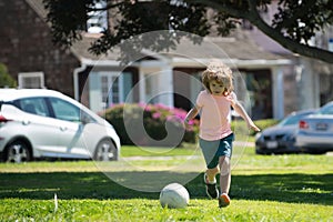 Excited child boy kicking ball in the grass outdoors. Soccer kids, children play football. Child soccer play football in