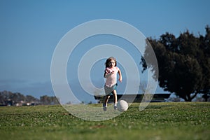 Excited child boy kicking ball in the grass outdoors. Soccer kids, children play football. Kids training soccer.