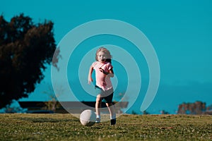 Excited child boy kicking ball in the grass outdoors. Soccer kids, children play football. Kids training soccer.