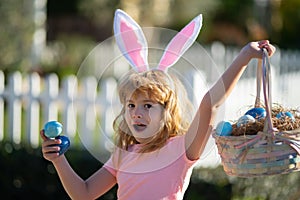 Excited child with easter basket. Child boy hunting easter eggs. Kid with easter eggs and bunny ears outdoor.
