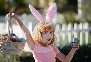 Excited child with easter basket. Child boy hunting easter eggs. Kid with easter eggs and bunny ears outdoor.
