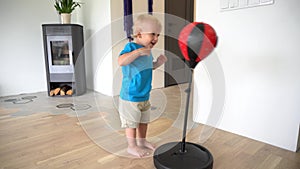 Excited child hitting pear. First time boxing. Cute blond boy. Gimbal motion