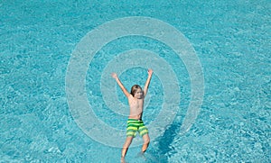 Excited child splashing water in pool. Little kid splashing in blue water of swimming pool. Cute boy swimming and