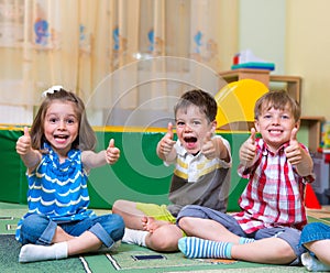 Excited children holding thumbs up photo