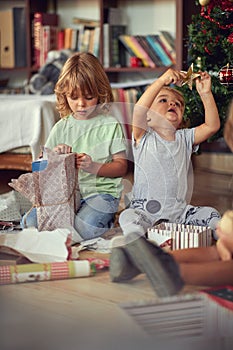 Excited Children Opening Presents By Tree On Christmas Morning