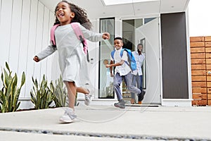 Excited Children Running Out Of Front Door On Way To School Watched By Father