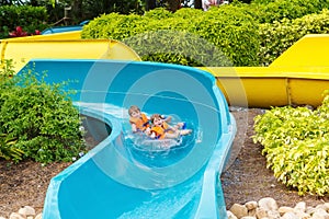 Excited children in water park riding on slide with float