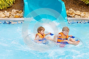 Excited children in water park riding on slide with float