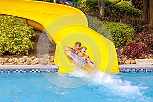 Excited children in water park riding on slide with float