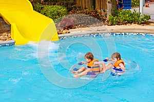 Excited children in water park riding on slide with float