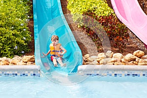 Excited children in water park riding on slide with float