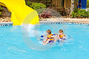 Excited children in water park riding on slide with float