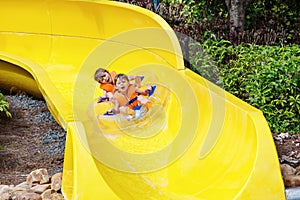 Excited children in water park riding on slide with float