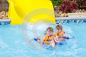 Excited children in water park riding on slide with float