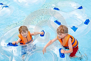 Excited children in water park riding on slide with float