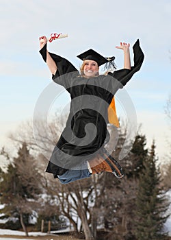 Excited college graduate jumping high into air