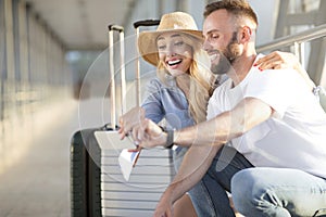 Excited couple in airport using smartphone, searching sightseeings