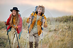 excited couple with bag pack on back holding hiking pole during hiking jurney.