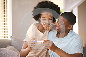 Excited Couple In Bedroom At Home Celebrating Positive Pregnancy Test Result