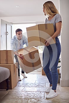 Excited Couple Carrying Boxes Through Front Door Of New Home On Moving Day